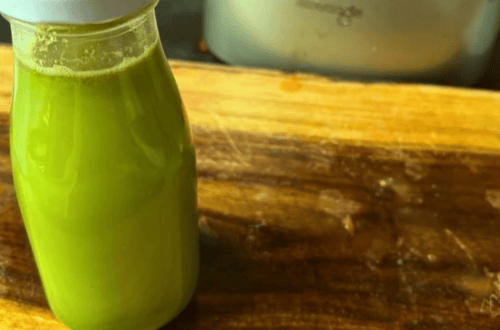 Fresh green juice in a glass bottle on a wooden surface.