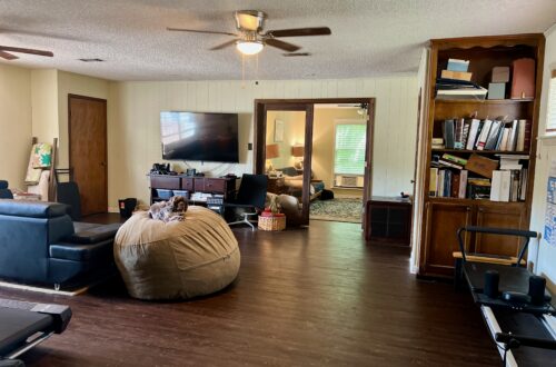 Cozy living room with TV, bookshelf, and bean bag chair for relaxation.