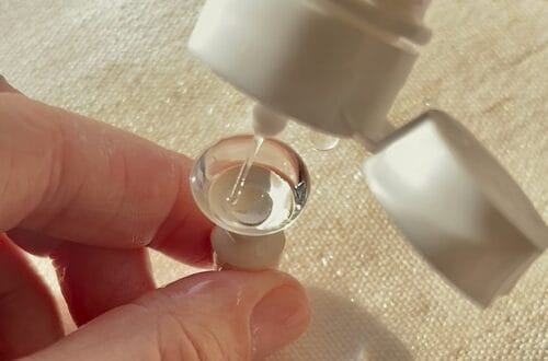 Close-up image of a hand holding a scleral contact lens filled with saline solution.