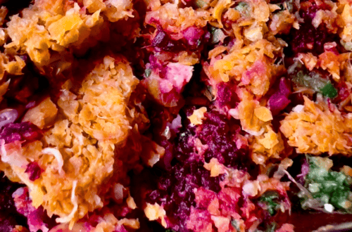 Close-up of a fruit crisp with a golden, crunchy topping and vibrant berry filling.