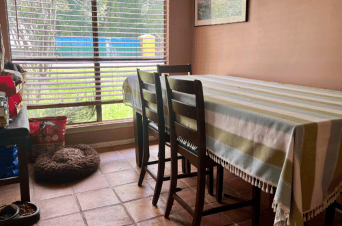 Bright dining room with striped tablecloth and large window.