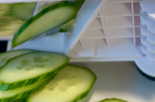 Fresh cucumber slices next to a food processor for healthy meal prep.