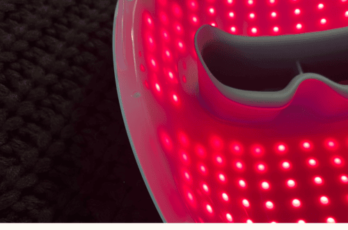 Red LED face mask for skincare with bright red lights and black interior.