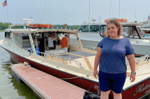 Woman enjoying a day at the marina with boats in the background.