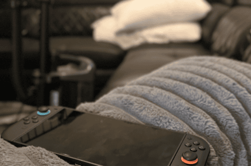 Nintendo Switch console on a cozy couch with blanket and pillows.