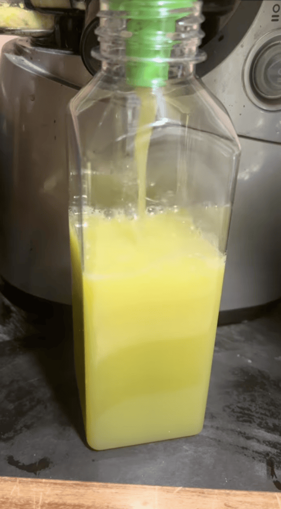 Homemade lemon juice being poured into a glass bottle for fresh use.