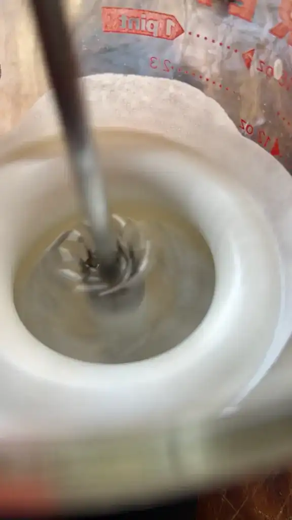 Close-up of the push whisk mixing ingredients in a kitchen setting.