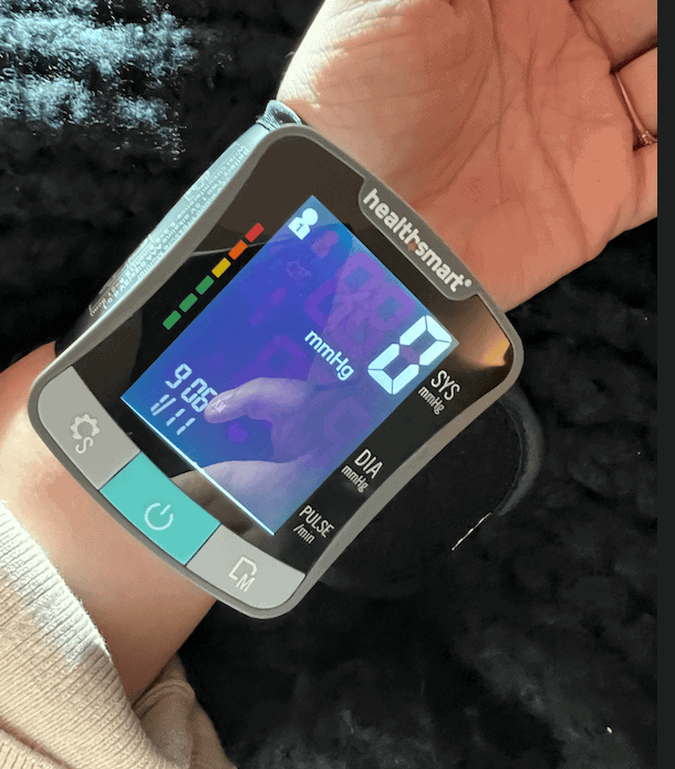 Woman using FSA eligible digital blood glucose monitor displaying 0.0 mmol/L reading.