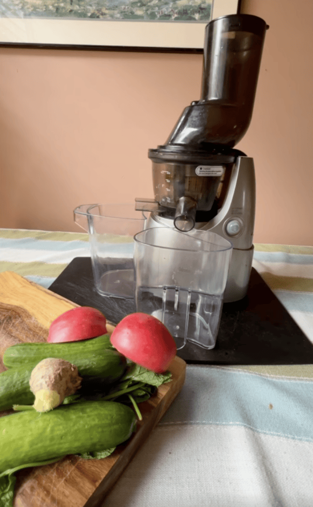 Electric juicer extracting juice from fresh vegetables and fruits.