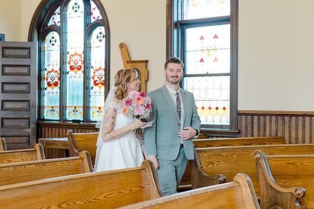 Natasia and Ed walking down the aisle at the Ottawa Wedding Chapel surrounded by wooden pews and stained glass windows