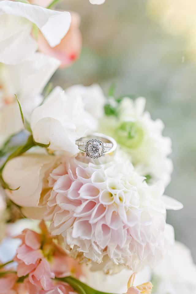 Engagement ring resting on a blush and white floral arrangement before the fall wedding at Lago