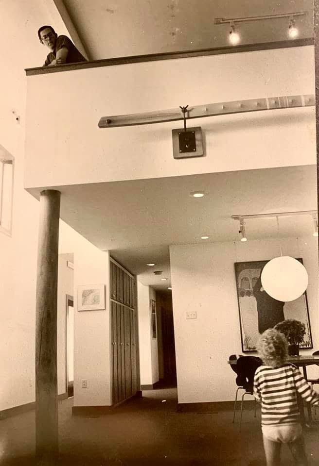 Modern interior with mezzanine, pendant light, and child in striped shirt.