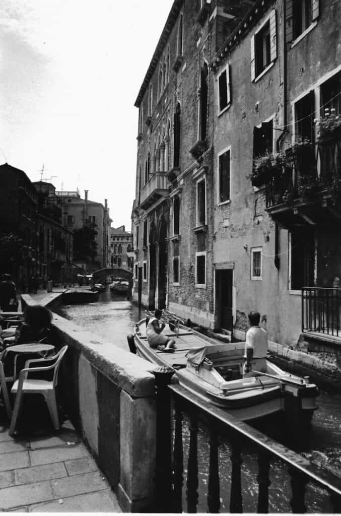 Black and white photo of a canal with boats and historic buildings in Venice.