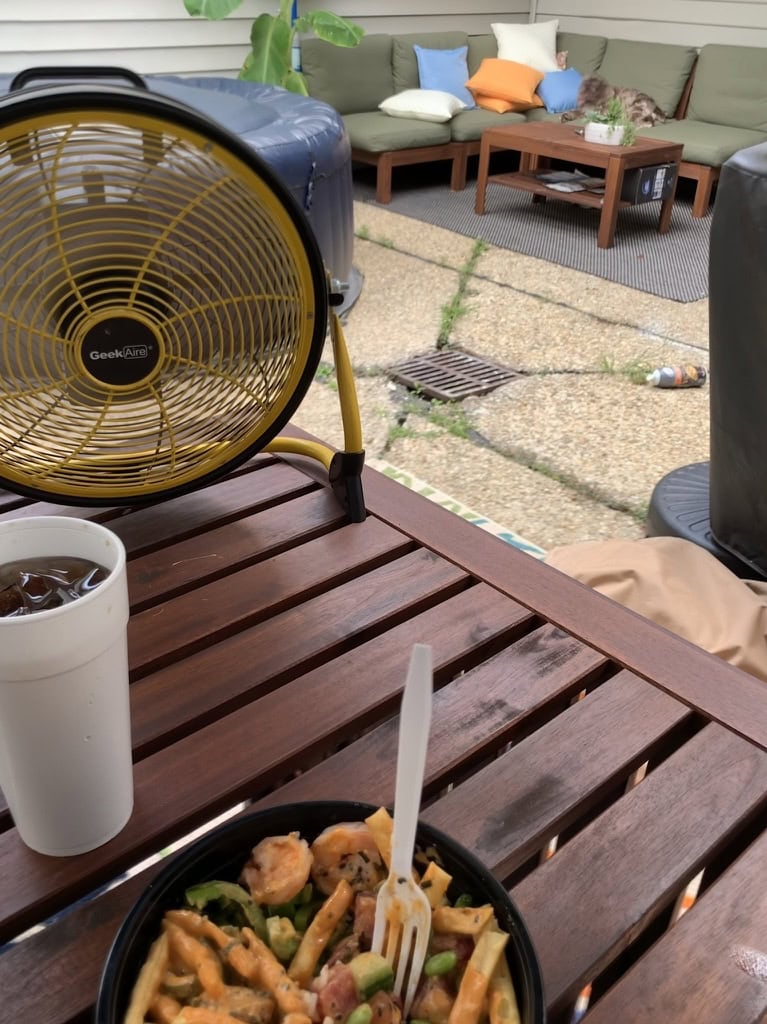 Cozy outdoor patio with seating, table, and fan for outdoor living.