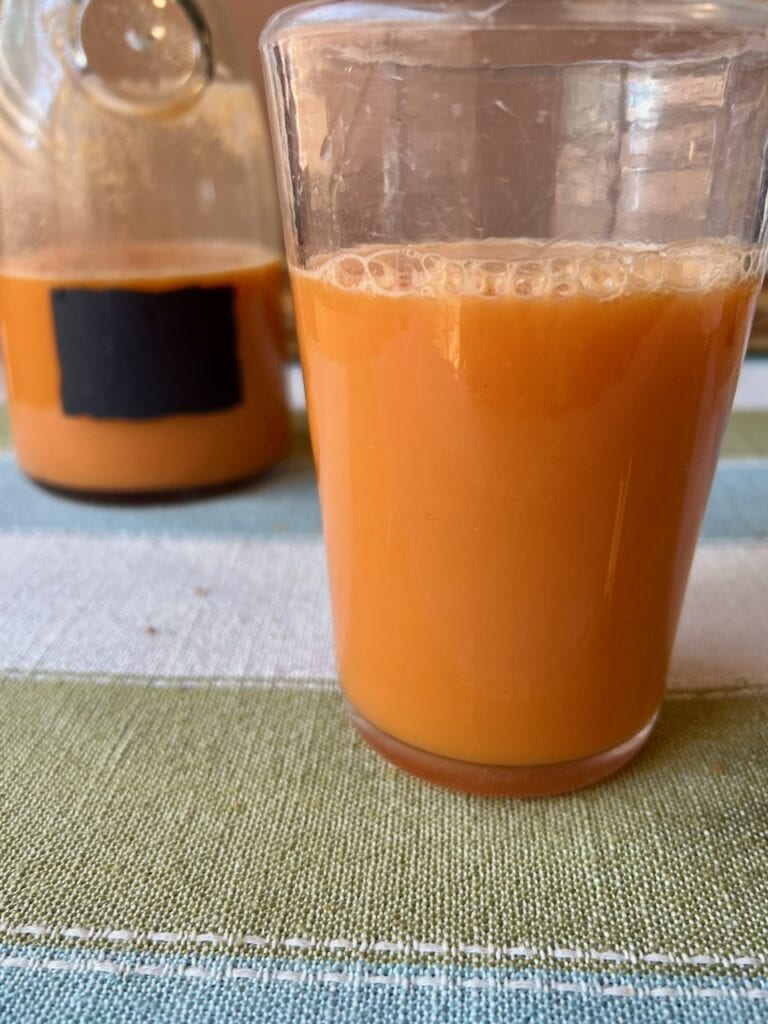 Glass of fresh orange juice with a bottle in the background.