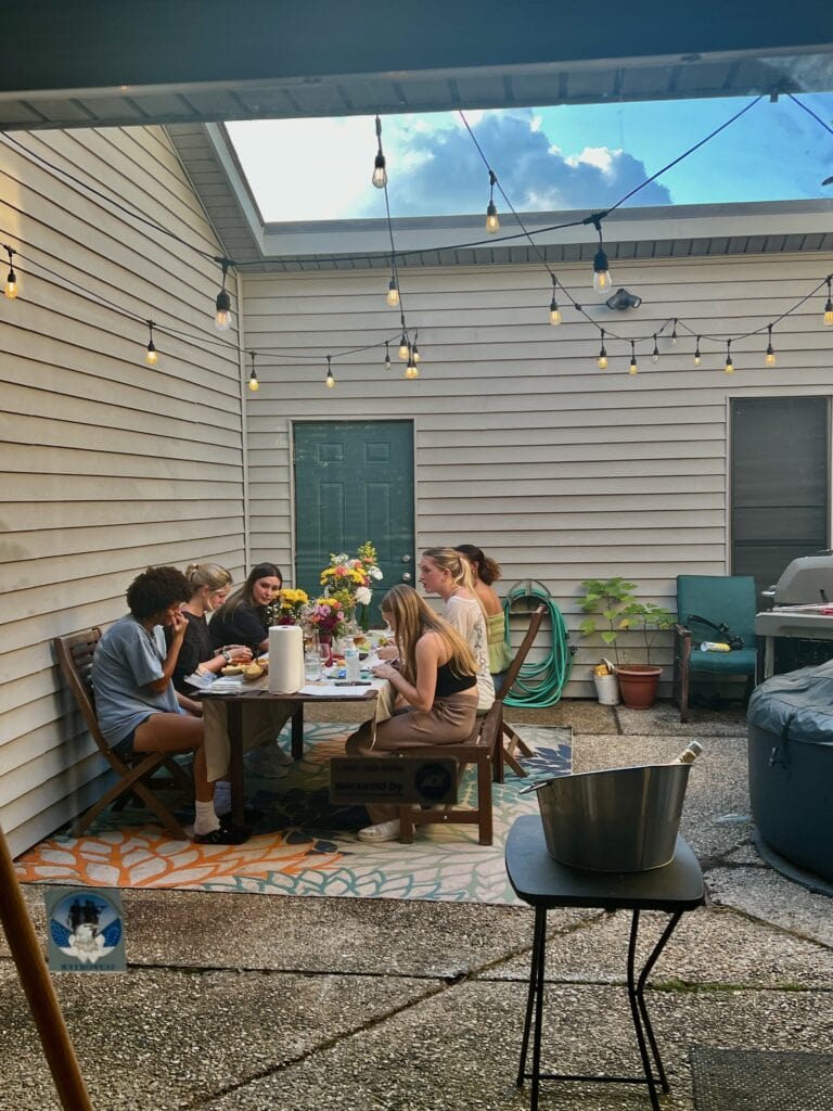 Group of friends enjoying outdoor dining under string lights.