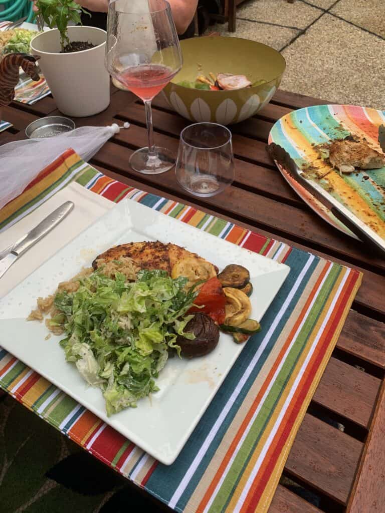 Outdoor dining with colorful plates, wine glass, and fresh food.