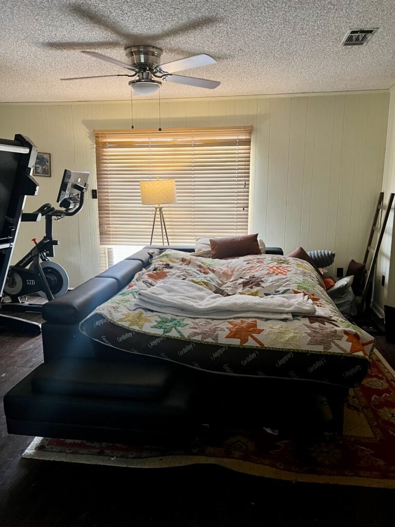 Cozy bedroom with a bed, exercise bike, and window with blinds.