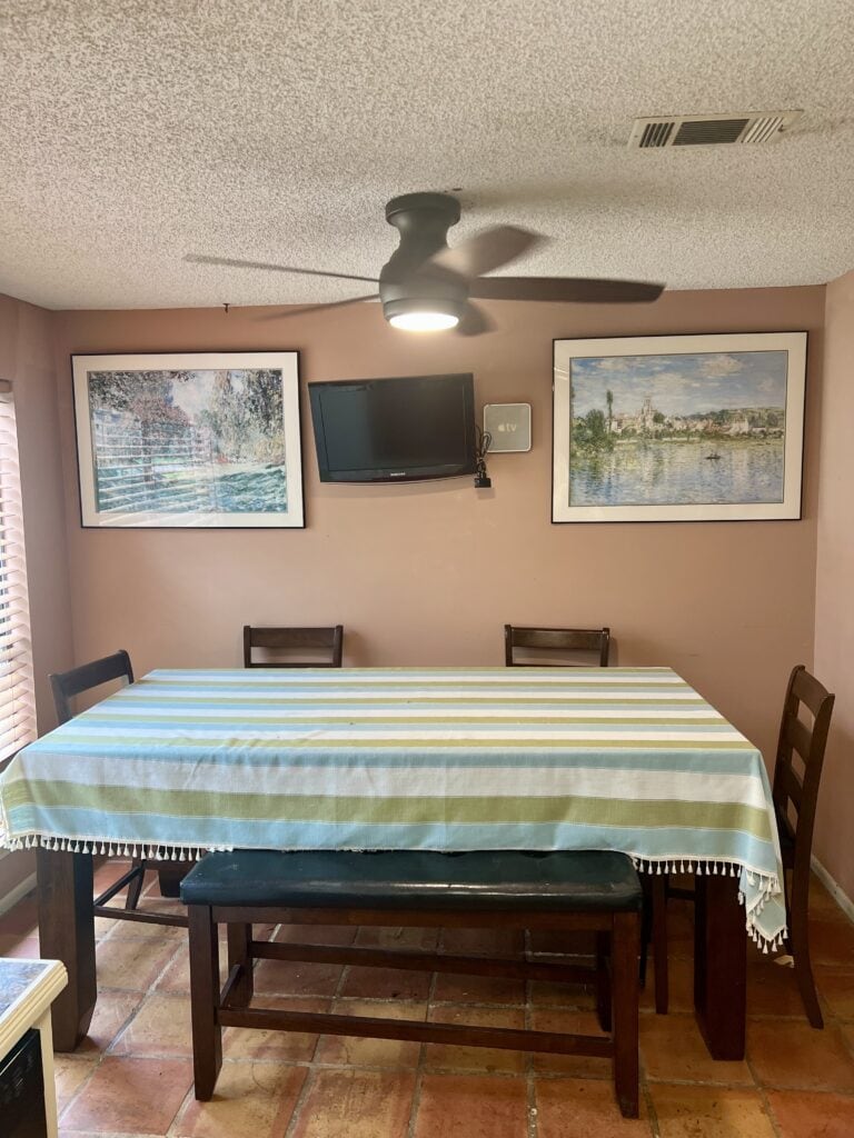 Dining room with table, chairs, wall art, and wall-mounted TV.