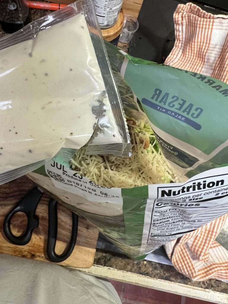 Fresh pasta with creamy sauce and salad on a kitchen counter.