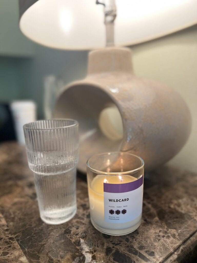 Decorative table lamp, candle, and glass on marble surface for home decor.
