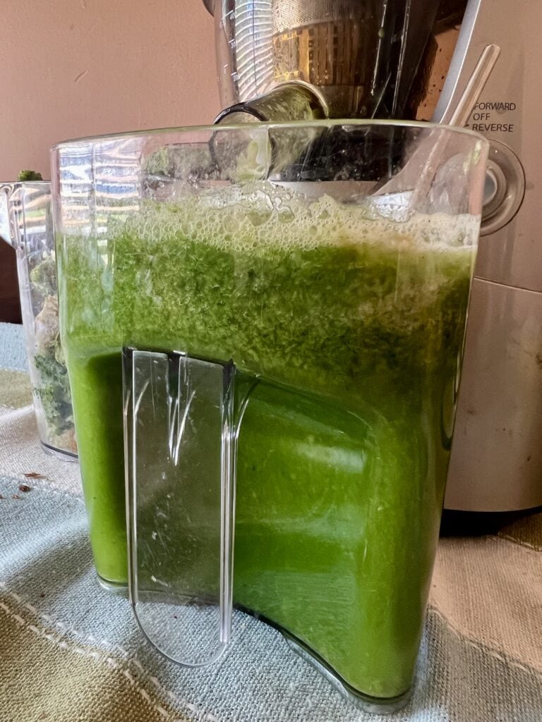 Green juice in a blender with a frothy top, ready to serve.