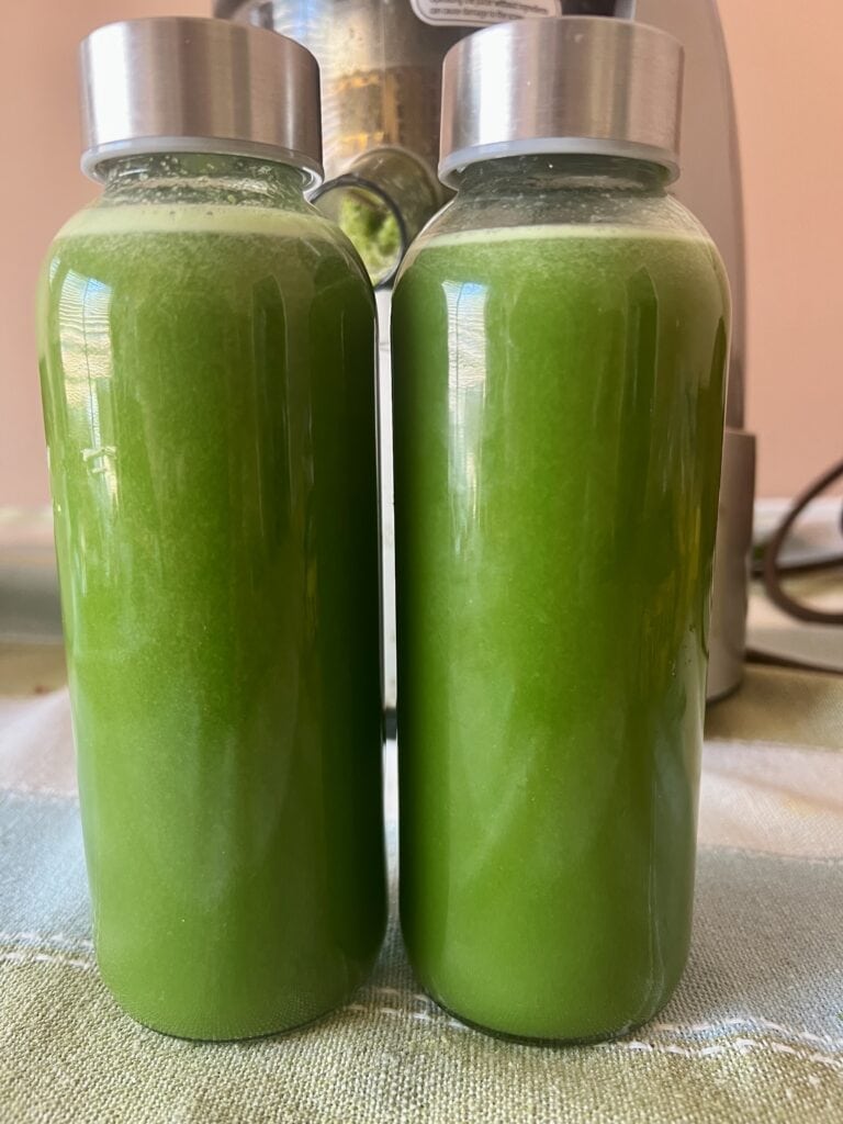 Two bottles of fresh green juice with stainless steel caps.