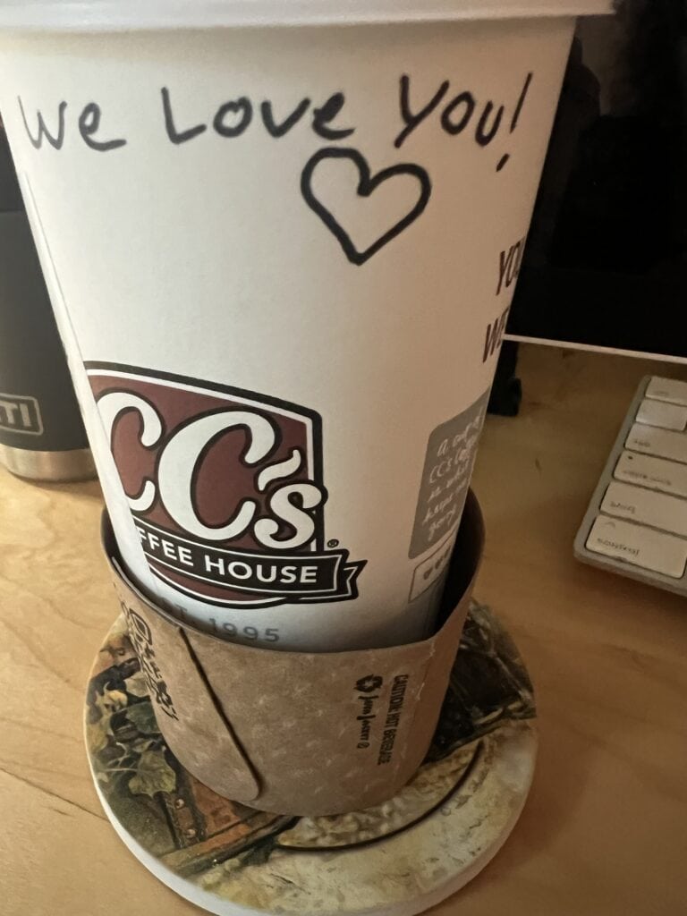Coffee cup with handwritten message 'We Love You!' and heart symbol.