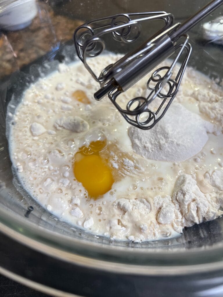 Mixing eggs and flour in a glass bowl for baking at Redcypress Designs.