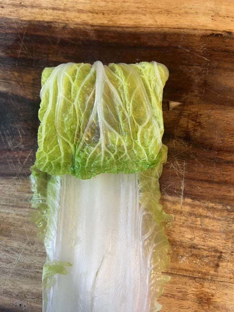 Close-up of a fresh, green lettuce leaf on a wooden surface.