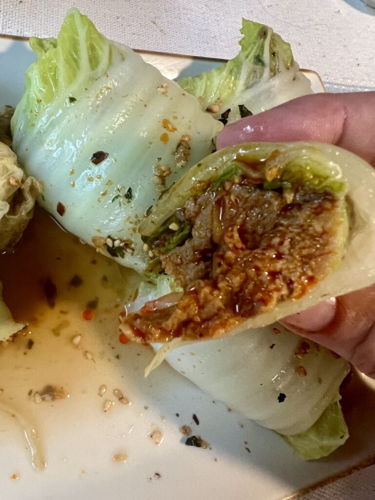 Close-up of a stuffed lettuce wrap with seasoned meat and vegetables.