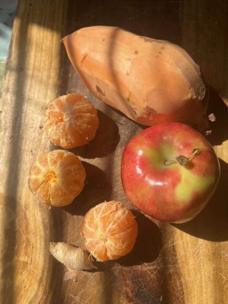 Fresh apple and citrus on wood cutting board with bread loaf.