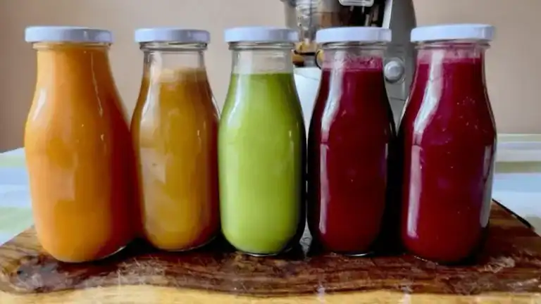 Assorted fresh juice bottles with vibrant colors on a wooden surface.