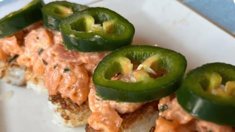 Delicious crispy rice bites topped with spicy salmon and jalapeño slices, perfect for quick sushi sn.
