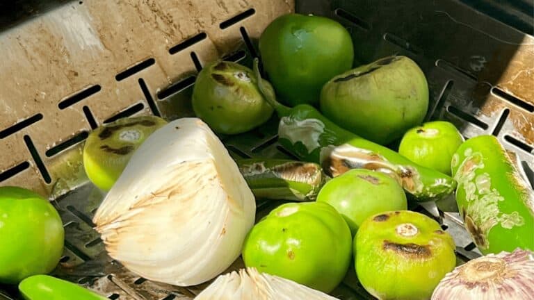 Fresh green tomatoes and sliced onion on a wire rack for cooking or preservation.