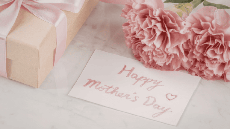 Mother’s Day gift with pink flowers, gift box, and handwritten card.