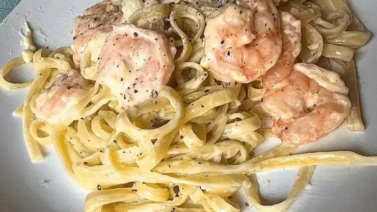 Creamy shrimp Alfredo served over fettuccine pasta with black pepper garnish.