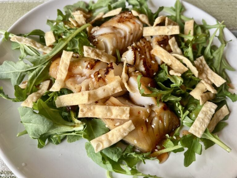 Miso-marinated black cod served over baby arugula with sweet chili sauce, sesame seeds, and crispy wonton strips.