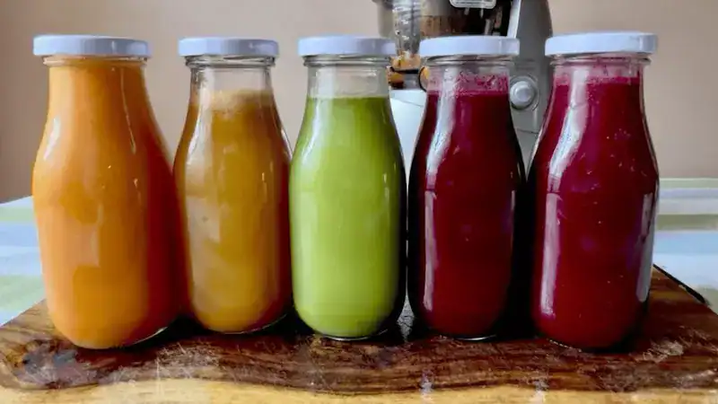 Assorted fresh juice bottles with vibrant colors on a wooden surface.
