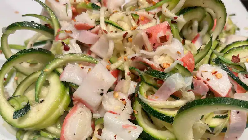 Fresh zucchini noodles with crab meat and spices for a healthy dish.