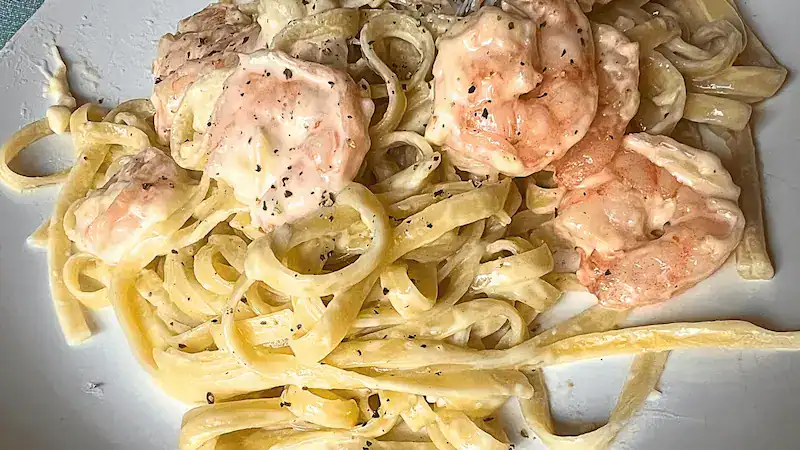 Creamy shrimp Alfredo served over fettuccine pasta with black pepper garnish.