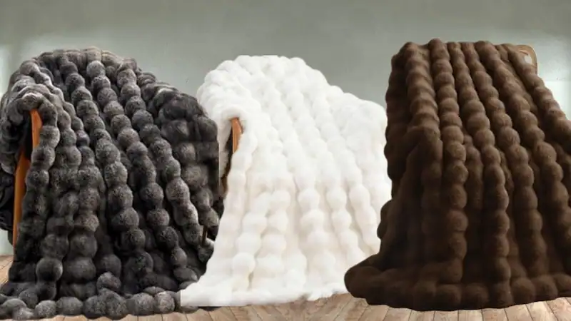 Cozy faux fur blankets in gray white and brown displayed together.
