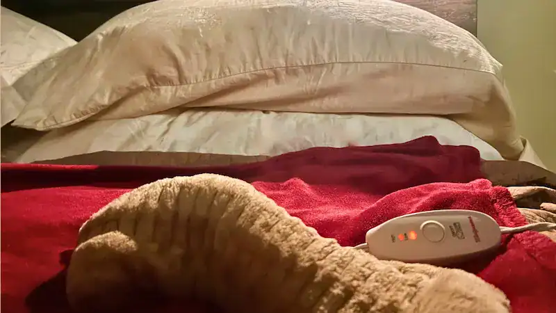 Heated blanket on bed with pillows for a warm, cozy bedroom atmosphere.