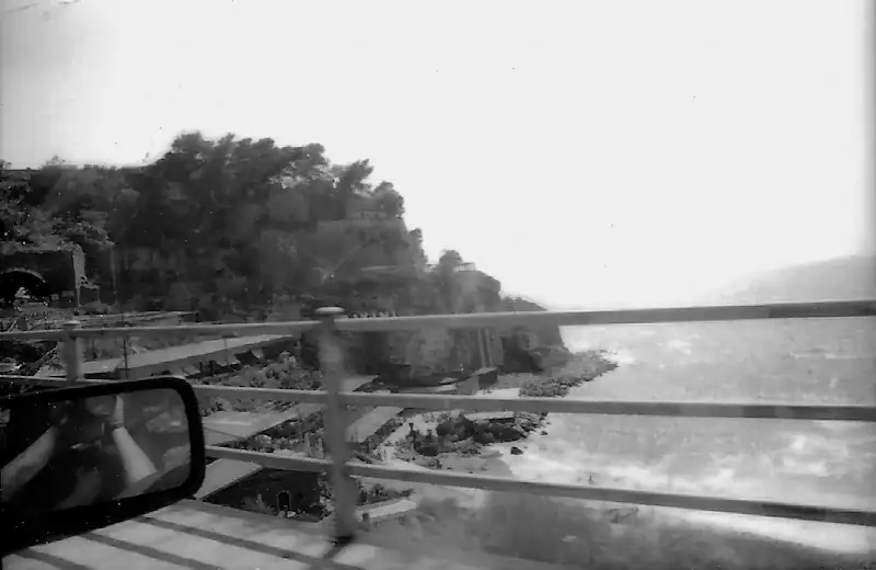 Scenic coastal road with cliffs and ocean view in black and white.