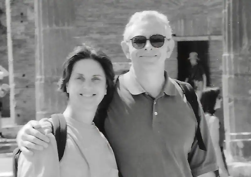 Smiling man and woman outdoors, casual attire, sunny day, black and white photo.