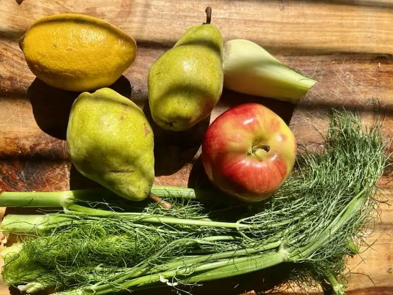 Assorted fresh fruits and dill on a rustic wooden surface.