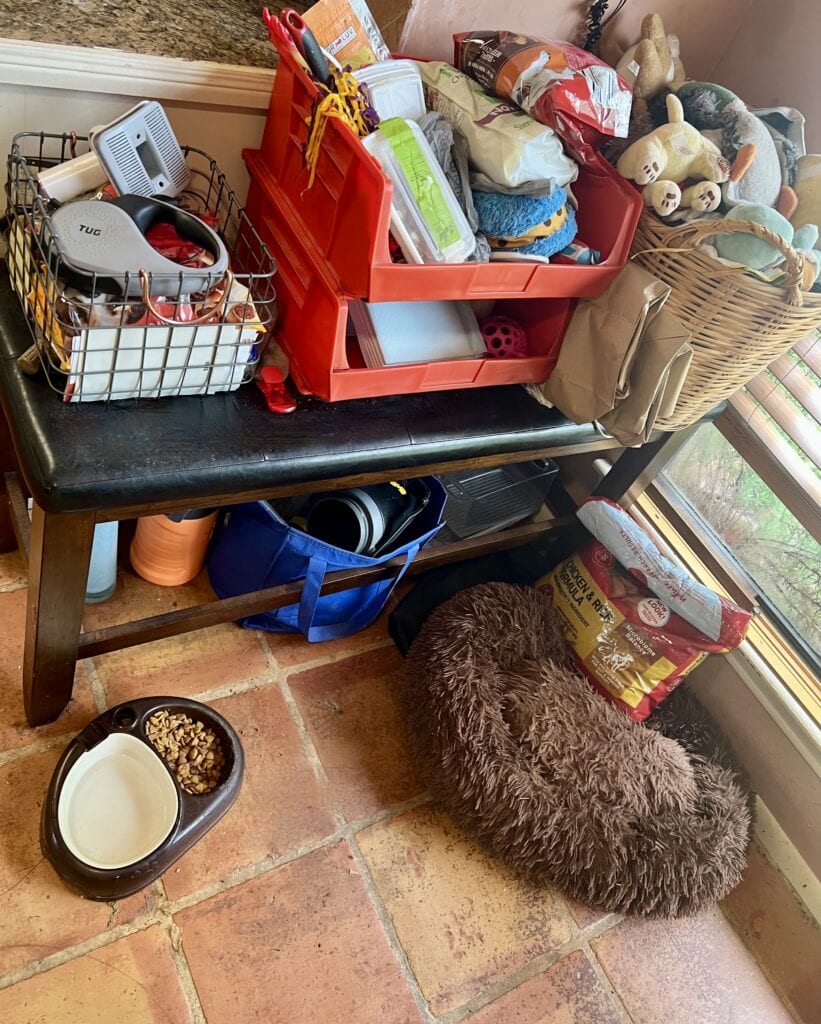 Toy and pet supplies organized on a brown bench with a dog bed nearby.