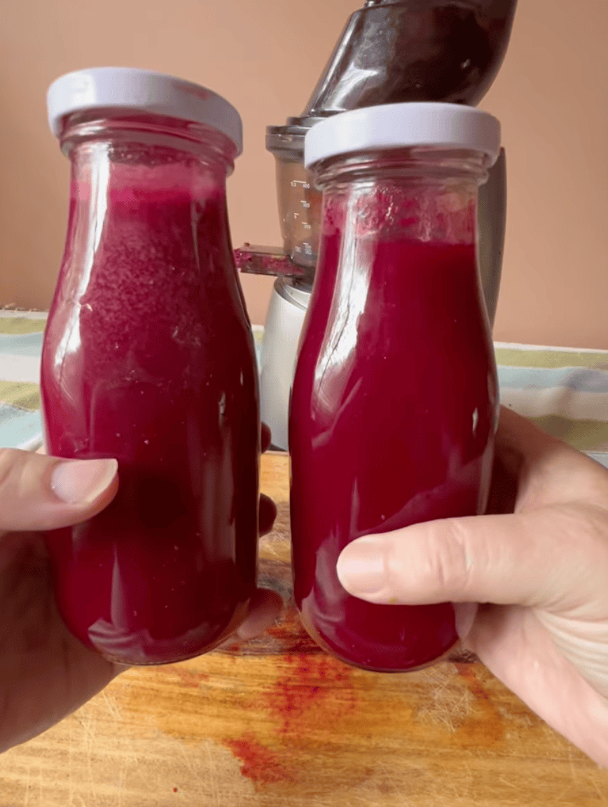 Two glass jars filled with homemade berry jam, held by hands, on a wooden surface.