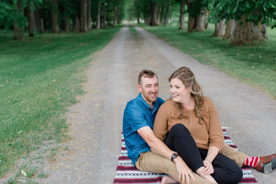 Laughing together - Fun on the Farm - Farm Engagement Session - Blue and Brown Engagement Session Inspiration - Natural Engagement Session Posing - Ideas for what to wear for Engagement Photography, Modern Engagement Session Inspiration Wardrobe Ideas. Unsure of what to wear for your engagement photos, we've got you! Romantic brown with black leggings for Summer Engagement in Almonte. Grey Loft Studio is Ottawa's Wedding and Engagement Photographer for Real couples, showcasing photos that are modern, bright, and fun.