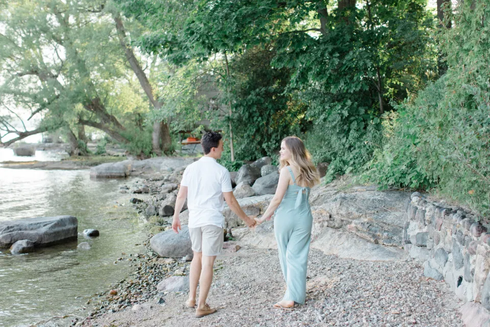 Looking at Each other Pose - Ideas for what to wear for Engagement Photography, Modern Engagement Session Inspiration Wardrobe Ideas. Unsure of what to wear for your engagement photos, we've got you! Romantic blue Romper and neutral Shirts and polo. Boat Shoes and Flip Flops. Engagement in Gananoque. Grey Loft Studio is Ottawa's Wedding and Engagement Photographer Videographer for Real couples, showcasing photos that are modern, bright, and fun.